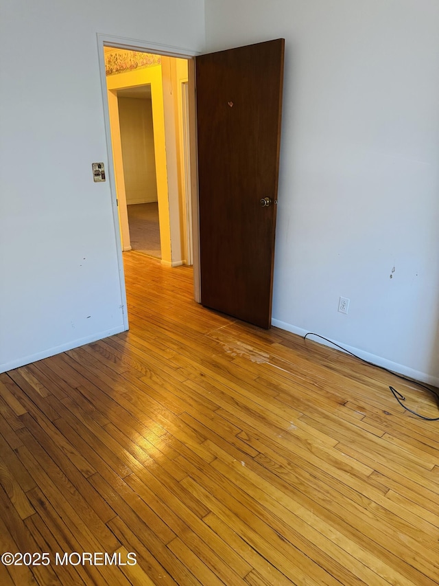 spare room featuring baseboards and light wood finished floors