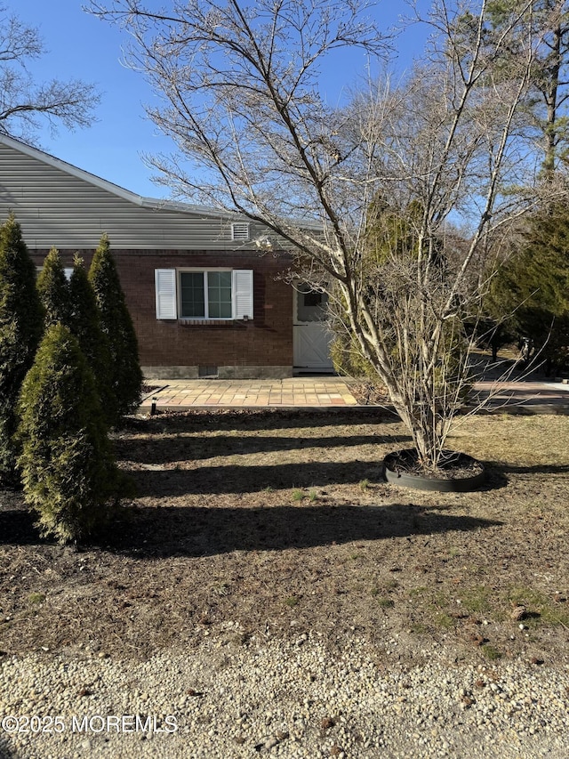 exterior space featuring brick siding and a patio area