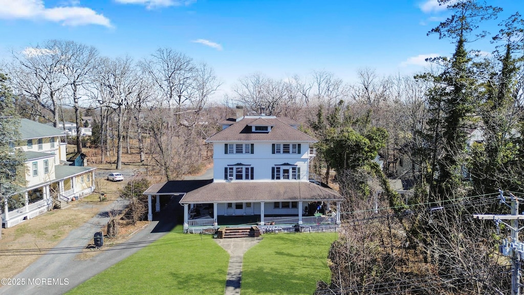 view of front of home with a front yard, covered porch, driveway, and a chimney