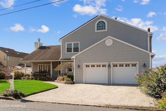 view of front facade featuring a front yard, covered porch, a chimney, decorative driveway, and a garage