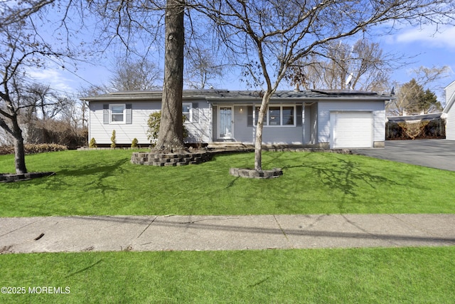 ranch-style home with aphalt driveway, solar panels, a front yard, and a garage