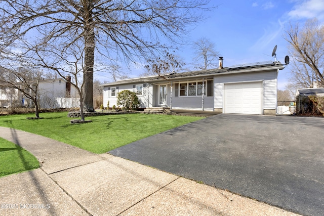 single story home with fence, a front lawn, a garage, aphalt driveway, and roof mounted solar panels