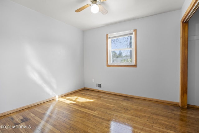 spare room with hardwood / wood-style flooring, baseboards, visible vents, and ceiling fan