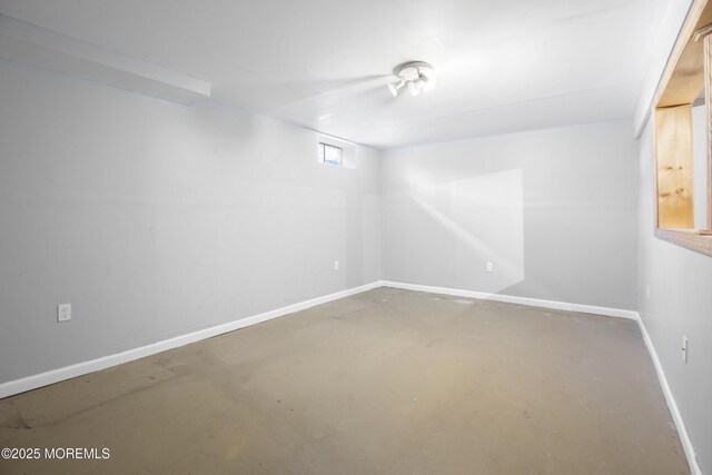 spare room featuring concrete flooring and baseboards