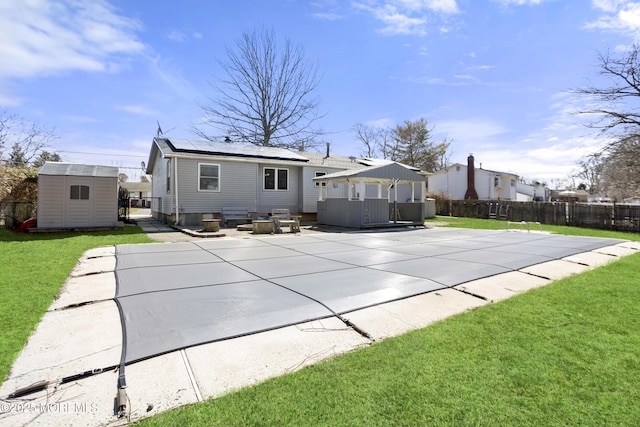 back of house featuring a patio area, a lawn, an outdoor structure, and fence