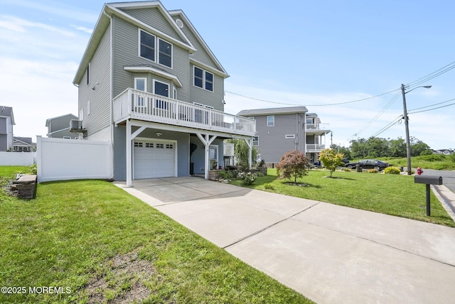 raised beach house featuring a garage, driveway, a front lawn, and fence