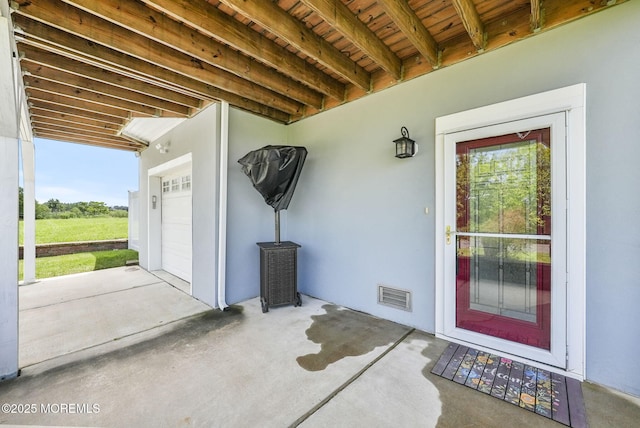 doorway to property featuring visible vents, stucco siding, driveway, and a garage