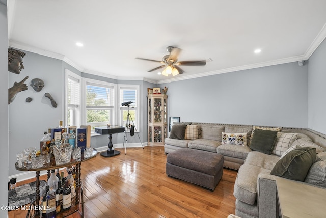 living area featuring ceiling fan, baseboards, wood-type flooring, and ornamental molding