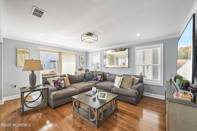 living room featuring visible vents, ornamental molding, baseboards, and hardwood / wood-style flooring