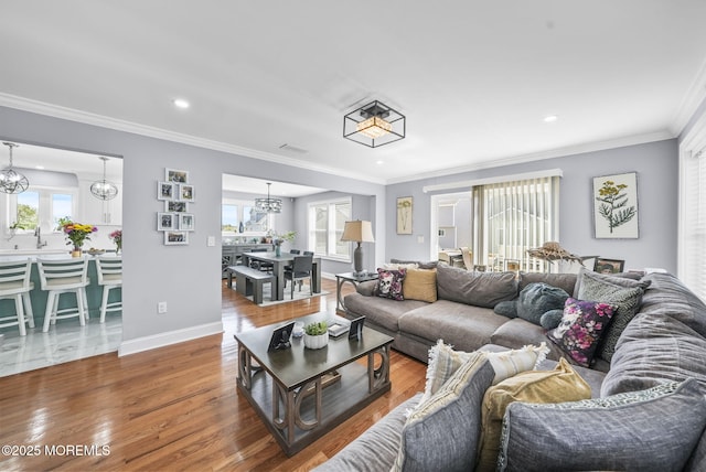 living room with wood finished floors, baseboards, an inviting chandelier, recessed lighting, and crown molding