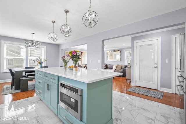 kitchen featuring light countertops, marble finish floor, a wealth of natural light, and a kitchen island