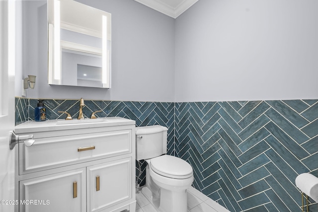 bathroom with a wainscoted wall, toilet, tile walls, crown molding, and vanity