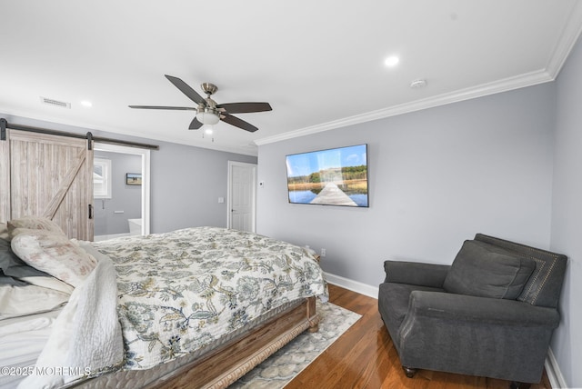 bedroom with dark wood finished floors, a barn door, crown molding, and baseboards