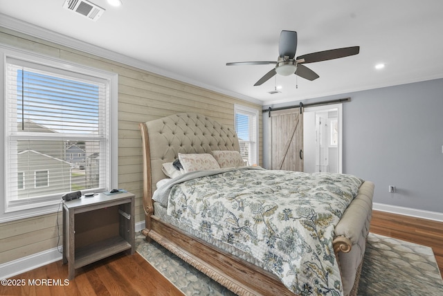 bedroom with dark wood-style floors, visible vents, baseboards, crown molding, and a barn door