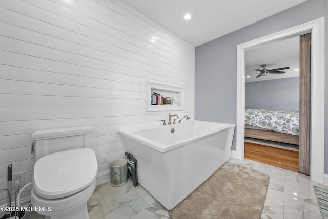 ensuite bathroom with connected bathroom, toilet, recessed lighting, a freestanding tub, and marble finish floor