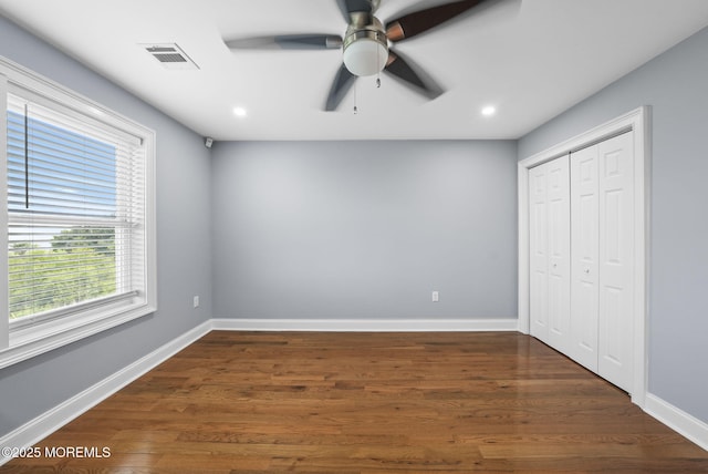 unfurnished bedroom featuring visible vents, baseboards, and dark wood-style flooring