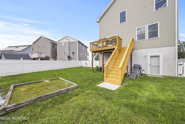 rear view of property with a deck, stairway, a yard, and fence