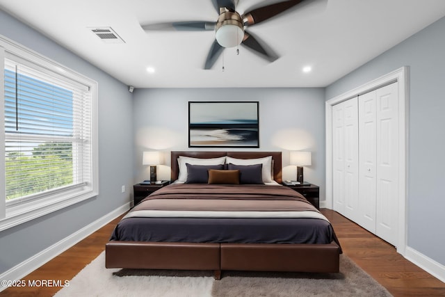 bedroom featuring visible vents, a ceiling fan, wood finished floors, a closet, and baseboards