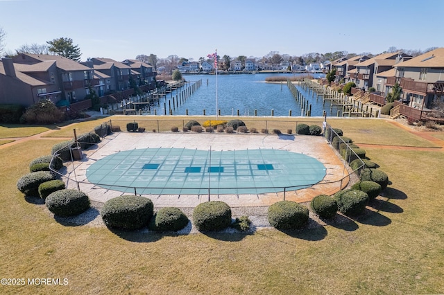 community pool with a residential view, a lawn, fence, and a water view