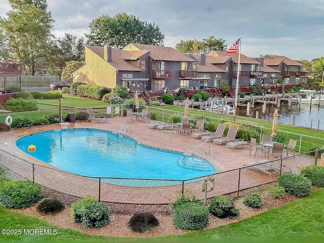 community pool featuring a residential view, fence, a lawn, and a patio area