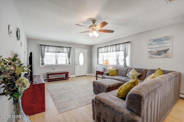 living room with a baseboard heating unit, plenty of natural light, light wood-style floors, and ceiling fan