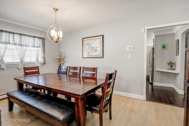 dining space with a chandelier, baseboards, light wood-style flooring, and a baseboard radiator