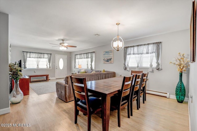 dining area with light wood-type flooring, baseboards, baseboard heating, and ceiling fan with notable chandelier