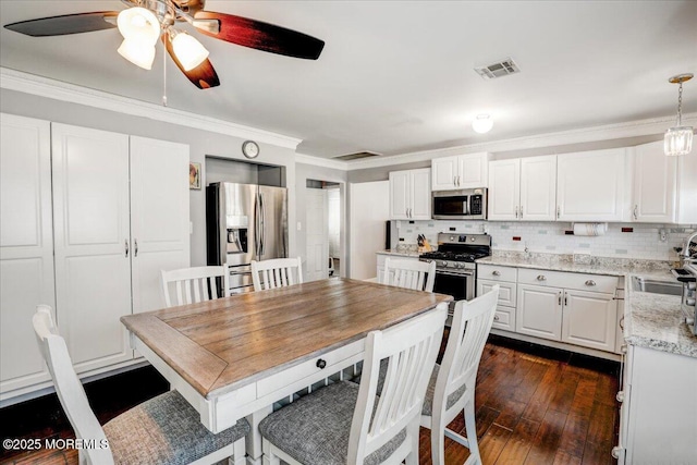 kitchen with stainless steel appliances, backsplash, visible vents, and ornamental molding