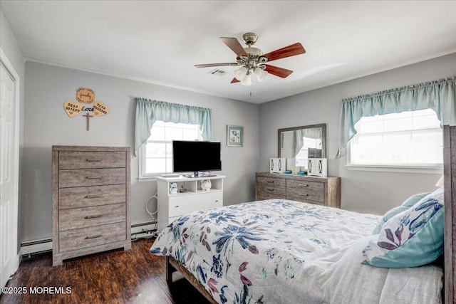 bedroom with multiple windows, dark wood-style flooring, baseboard heating, and ceiling fan