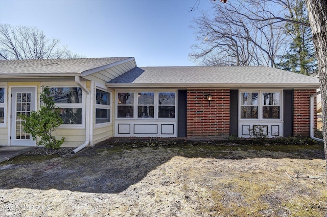 rear view of house with brick siding and roof with shingles