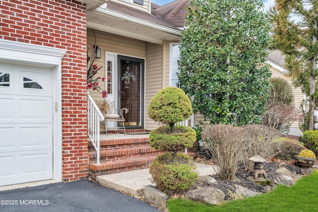 view of exterior entry with brick siding, an attached garage, and a shingled roof