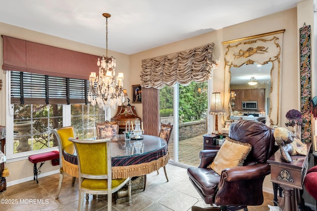 tiled dining space with baseboards and a chandelier