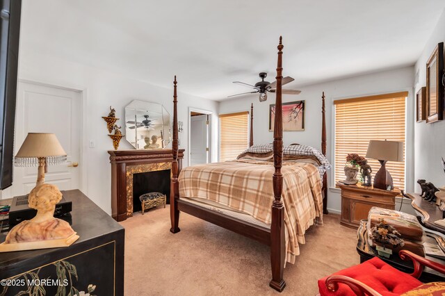 bedroom featuring light carpet, a ceiling fan, and a fireplace