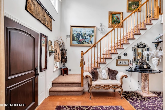 foyer entrance featuring baseboards, wood finished floors, and stairs