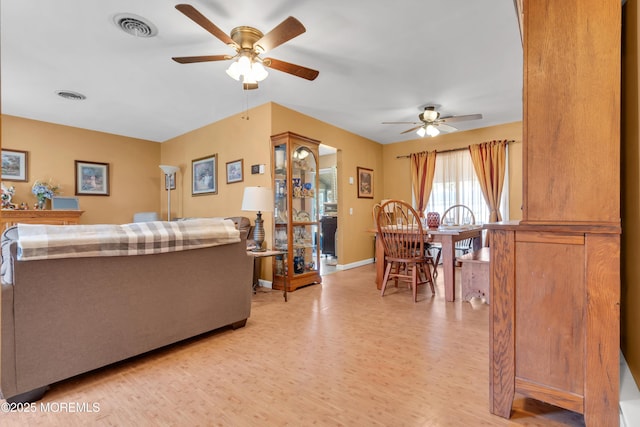 living room with light wood finished floors, visible vents, baseboards, and a ceiling fan