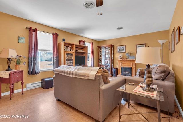 living room with visible vents, a fireplace, light wood finished floors, baseboards, and baseboard heating