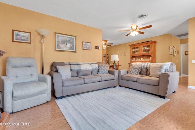 living area with visible vents, light wood-style flooring, baseboards, and a ceiling fan