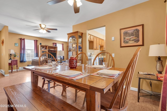 dining area featuring light wood-style flooring, a ceiling fan, and baseboards