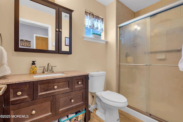 full bathroom featuring toilet, a stall shower, and vanity