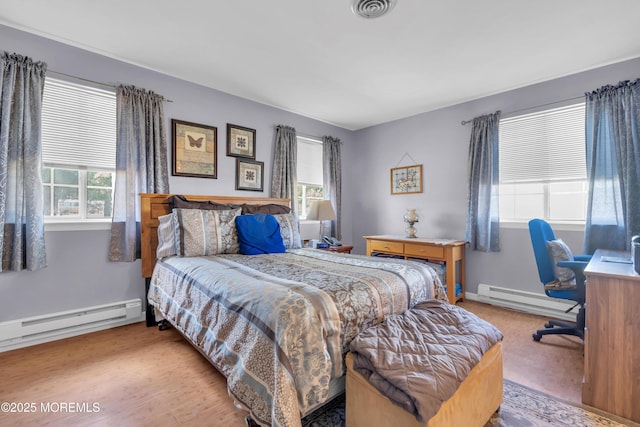 bedroom featuring wood finished floors, baseboards, visible vents, and a baseboard radiator