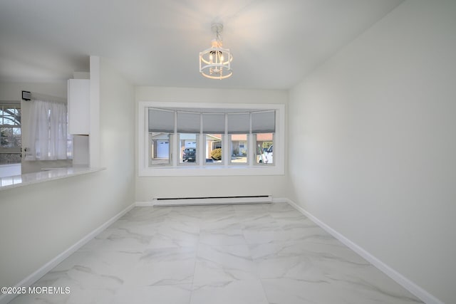 spare room with marble finish floor, a baseboard heating unit, and a healthy amount of sunlight