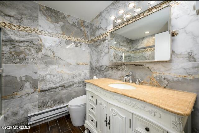 full bath featuring wood finish floors, a baseboard radiator, an enclosed shower, tile walls, and toilet