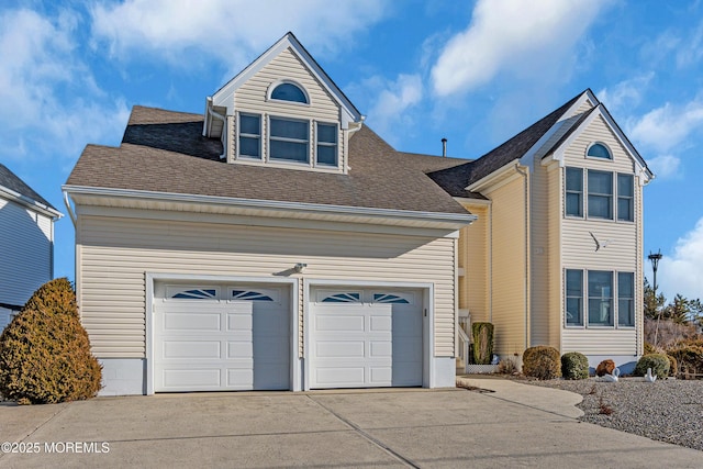 traditional-style home featuring roof with shingles, concrete driveway, and an attached garage