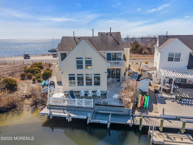 rear view of property with a balcony, a water view, and a shingled roof