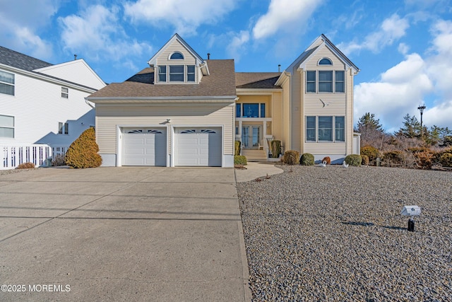 traditional-style home with an attached garage, concrete driveway, and roof with shingles