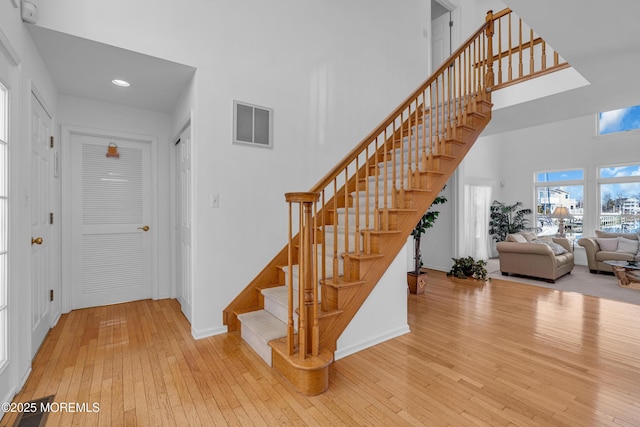 stairway with visible vents, a high ceiling, baseboards, and hardwood / wood-style floors