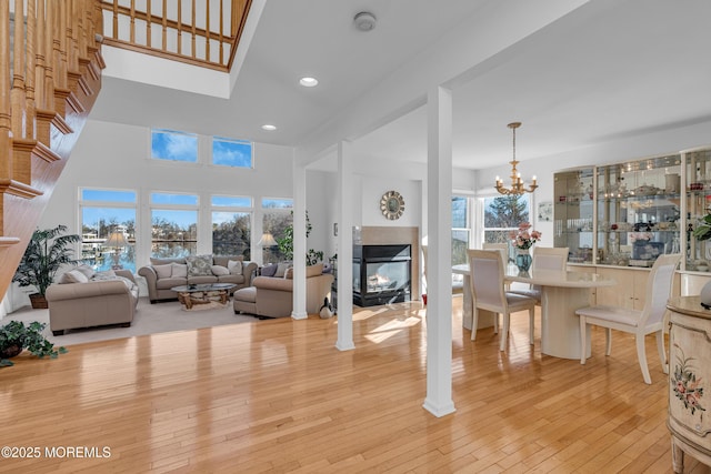 living room with a tiled fireplace, light wood-style flooring, a notable chandelier, and recessed lighting