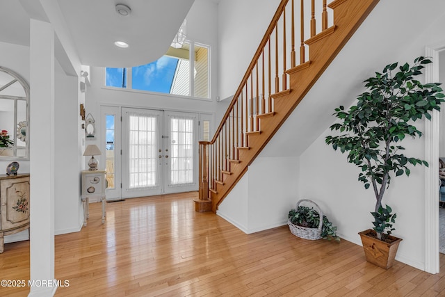 foyer entrance with french doors, stairs, a high ceiling, and hardwood / wood-style floors