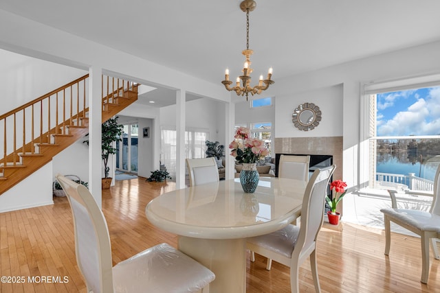 dining room featuring a chandelier, stairway, light wood-style floors, and a water view