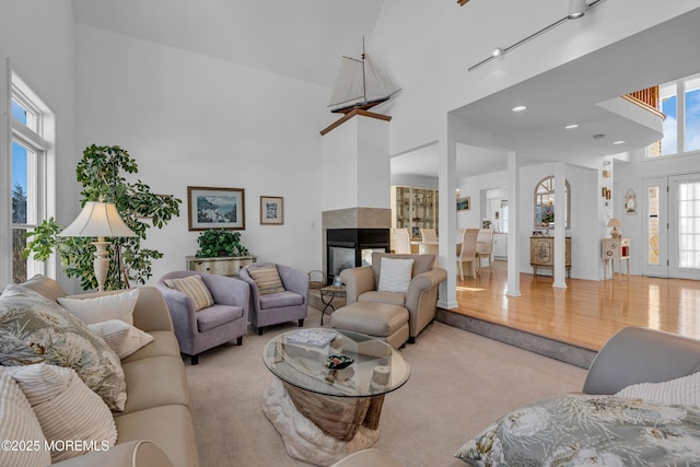 living area with a multi sided fireplace, light carpet, and a towering ceiling